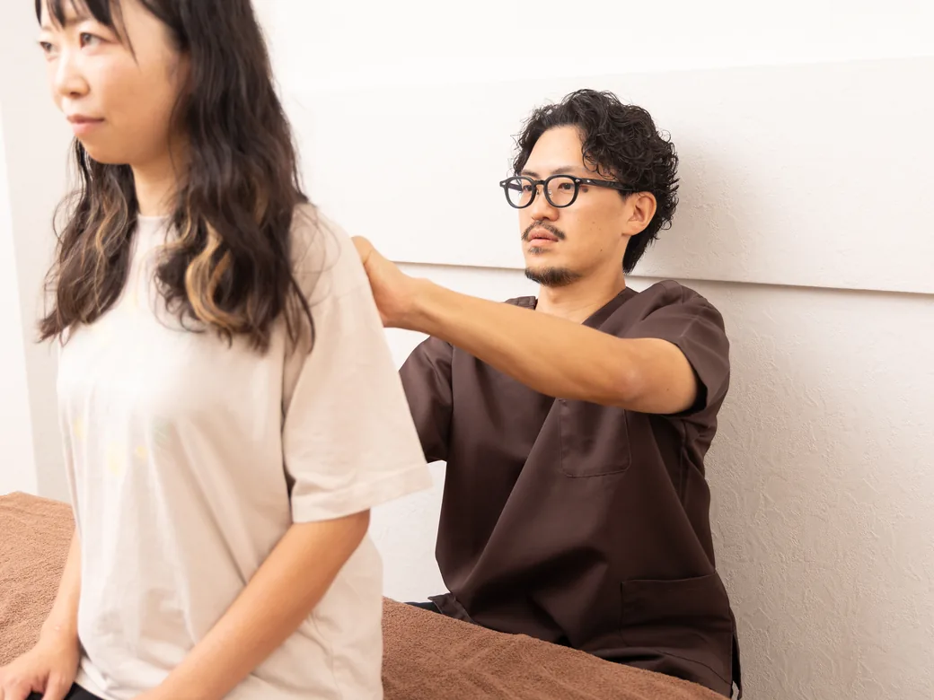 座った姿勢で肩・首まわりを確認する様子